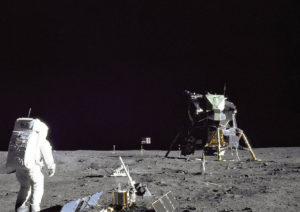 Buzz Aldrin sul suolo lunare, vicino a materiali per gli esperimenti e sullo sfondo il modulo dell'allunaggio